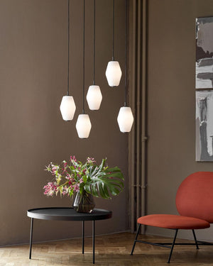 Modern interior with pendant lights, a table with flowers, and a red chair.