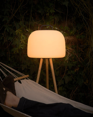 Lamp on a stand in a dark outdoor setting with a person lying in a hammock.