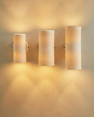 Three cylindrical wall lights on a beige wall