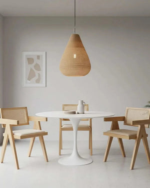Modern dining area with a white round table and wooden chairs, featuring a rattan teardrop pendant