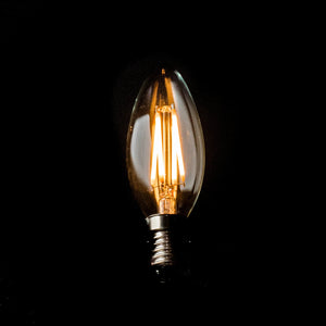 Vintage-style light bulb with clear glass and visible filament on a black background