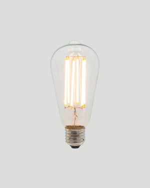 Clear light bulb with visible filaments on a gray background