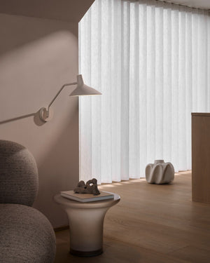 Modern interior with a lamp, small table, and decorative items in a room with large windows.
