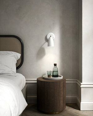 white wall sconce installed above timber bedside table
