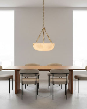 Alabaster bowl pendant light suspended above dining table in minimalist white interior