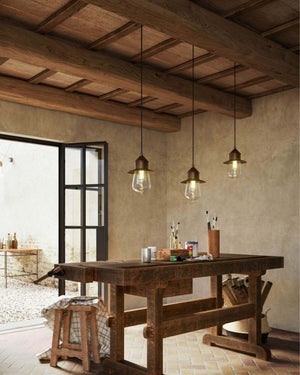 Three Antique Teardrop Pendant Lights hanging in an country artist room over a table