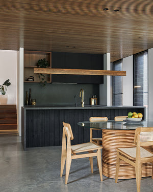 A dark industrial kitchen and dining area with wood accents and a timber linear pendant