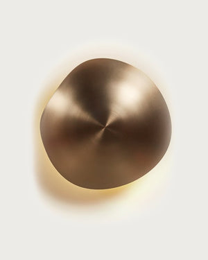 Brass wall sconce emitting a warm glow on a light grey background