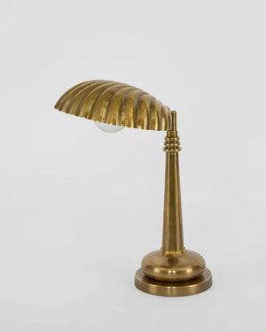 Brass shell table lamp viewed from the side showing tapered stem and round base