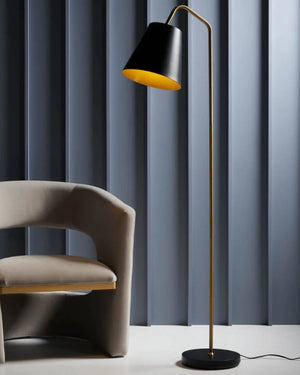 Modern floor lamp with black and gold design next to a chair against a blue curtain background