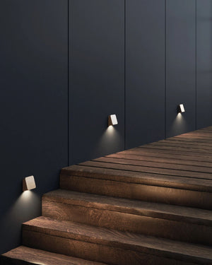 Wooden staircase with wall-mounted lights against a dark blue wall
