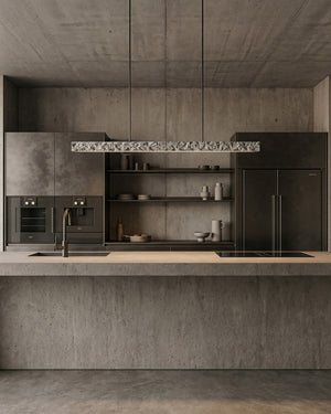 Concrete carst linear pendant light suspended above a brutalist style kitchen island 