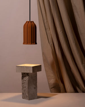 Earth Brown U Pendant lamp hanging above a concrete table