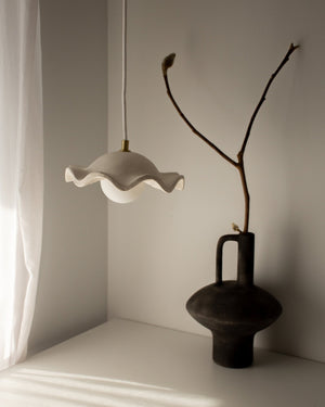 Ceramic wavy pendant next to black vase