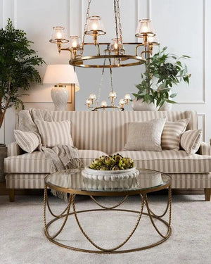 Living room with striped sofa, round glass coffee table, and decorative elements.