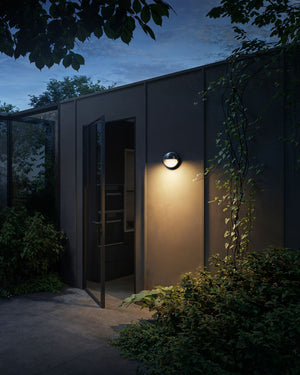 Modern outdoor building with a wall-mounted light fixture at night - Lighting Collective 