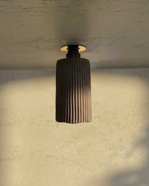 Concrete Wavy Downlight in charcoal mounted on ceiling casting warm downward light in atmospheric interior