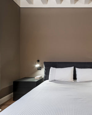 Modern bedroom with a bed, nightstand, and wall light fixture.