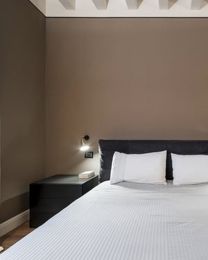 Modern bedroom with a bed, nightstand, and wall light fixture.