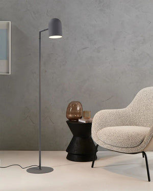 Modern interior with a gray floor lamp, black side table, and beige armchair against a gray wall.