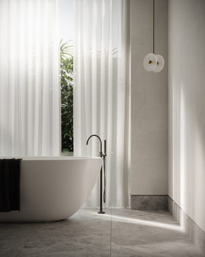Modern bathroom with a freestanding bathtub, sleek faucet, glass pendant, and large window with white curtains.