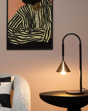 Modern interior with a brass lamp, round table, and abstract zebra print painting on a wall.