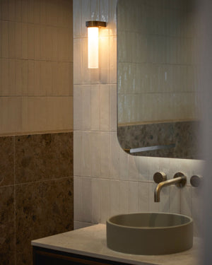 Cylindrical glass wall light styled in a contemporary minimalist bathroom