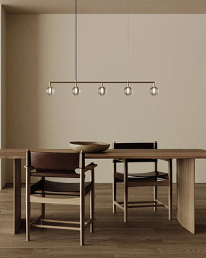Dining area with wooden table and chairs, modern pendant light, and neutral wall.