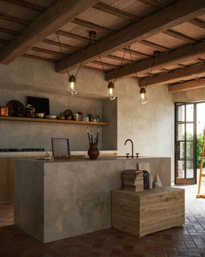 Dual Cable Pendant Light in antique brass suspended above concrete kitchen island in rustic interior