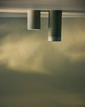 Two cylindrical Dusked ceramic ceiling lights casting shadows on a textured wall.