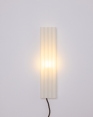 A modern vertical rectangular wall sconce with a pleated translucent shade light on
