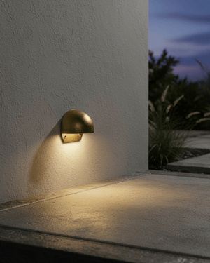 A round brass step light on an outdoor wall