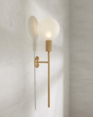Brass wall sconce with a white bulb on a light gray wall light on