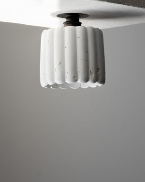 Ceiling light fixture with ribbed design on a plain background