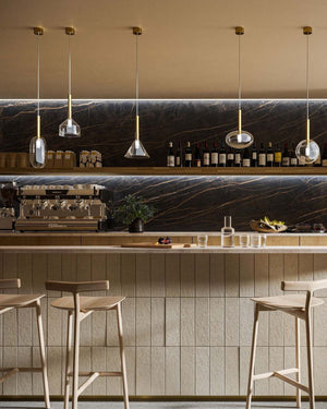 cluster of five brass and clear glass pendants with different shapes displayed over a bar table
