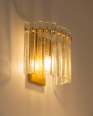 Decorative art-deco wall sconce with glass panels on a plain wall