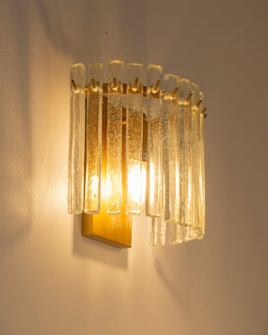 Decorative art-deco wall sconce with glass panels on a plain wall
