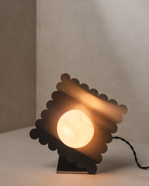 Wave Table Lamp styled with the scalloped disc tilted on an angle, warm light glowing through the steel