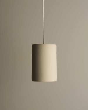 Beige cylinder pendant light against a beige wall