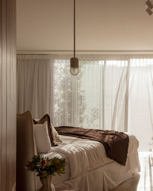 Modern bedroom with cylindrical pendant installed beside bed