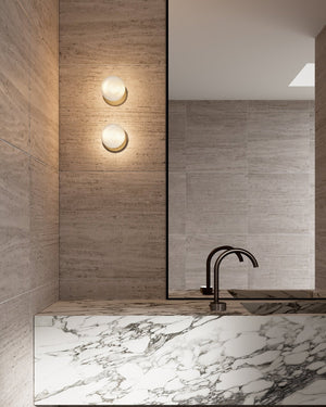 Two handmade sora frosted glass wall sconce mounted above a modern bathroom  with marble sink