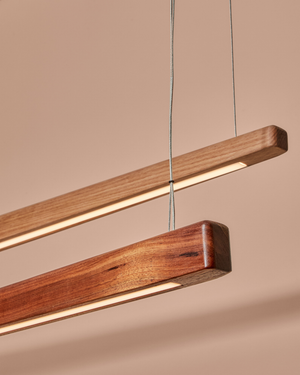 Close-up of two Handmade Timber Linear Pendant Shoreline lights in Victorian Ash and Blackwood showing lit LED strip
