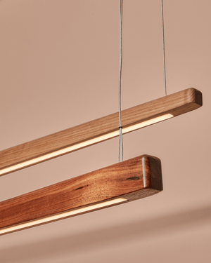 Close-up of two Handmade Timber Linear Pendant Shoreline lights in Victorian Ash and Blackwood showing lit LED strip