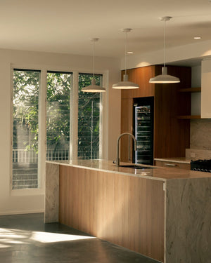 Three pendant lights suspended above a warm style kitchen bench