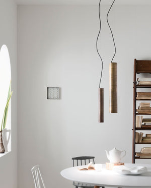 Two tubular pendants with antique iron and brass finishes hanging over a dining table