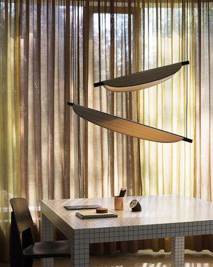 Modern room with a desk, chair, and wooden pendants in front of sheer curtains.