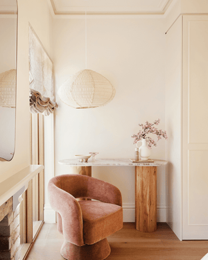 Three Birds House 18 Project - Maison Soleil: A warm, minimalist interior corner featuring a velvet accent chair, a marble-topped console table and a textured linen pendant light hanging from the ceiling.