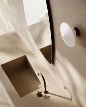 Diamond shaped wall light with bronze finish near a mirror in a bathroom