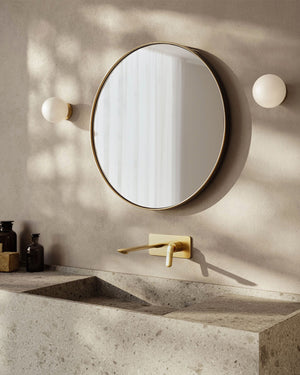 Italian spherical glass and brass wal lights on both sides of a mirror in a bathroom