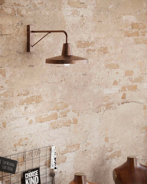 Pre aged iron wall light displayed in a bedroom with brick walls